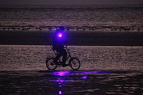 Am Wasser radelnder Bernsteinsucher mit UV-Scheinwerfer